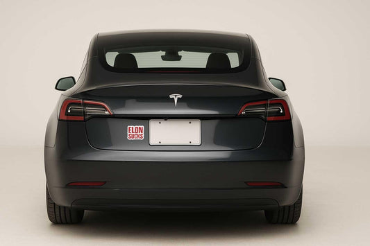 Black Tesla car with a custom license plate on a white background with a sticker that says ELON SUCKS