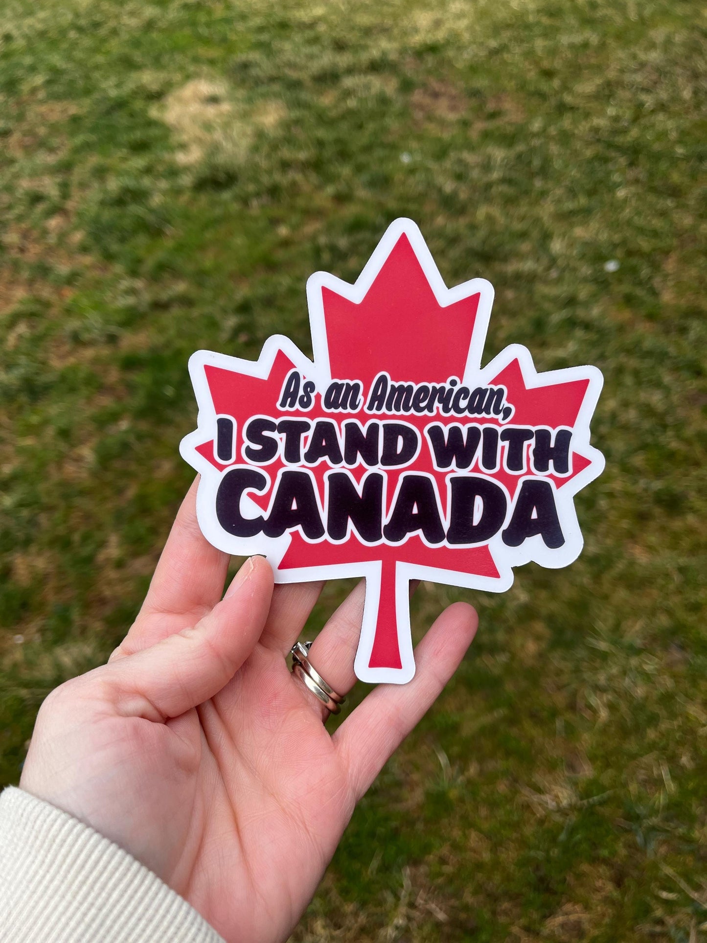 As an American, I Stand With Canada magnet held in hand, expressing support for Canadian allies and progressive unity