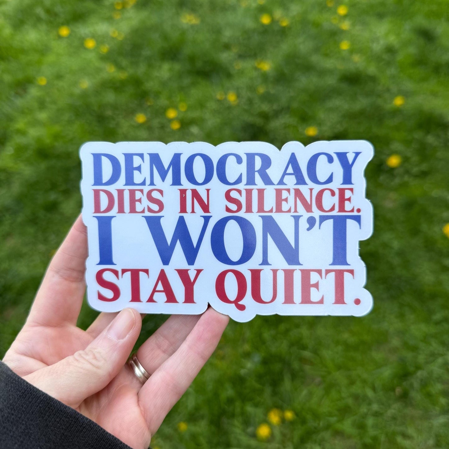 Democracy dies in silence. I won't stay quiet magnet held in hand, expressing defiance and civic responsibility.