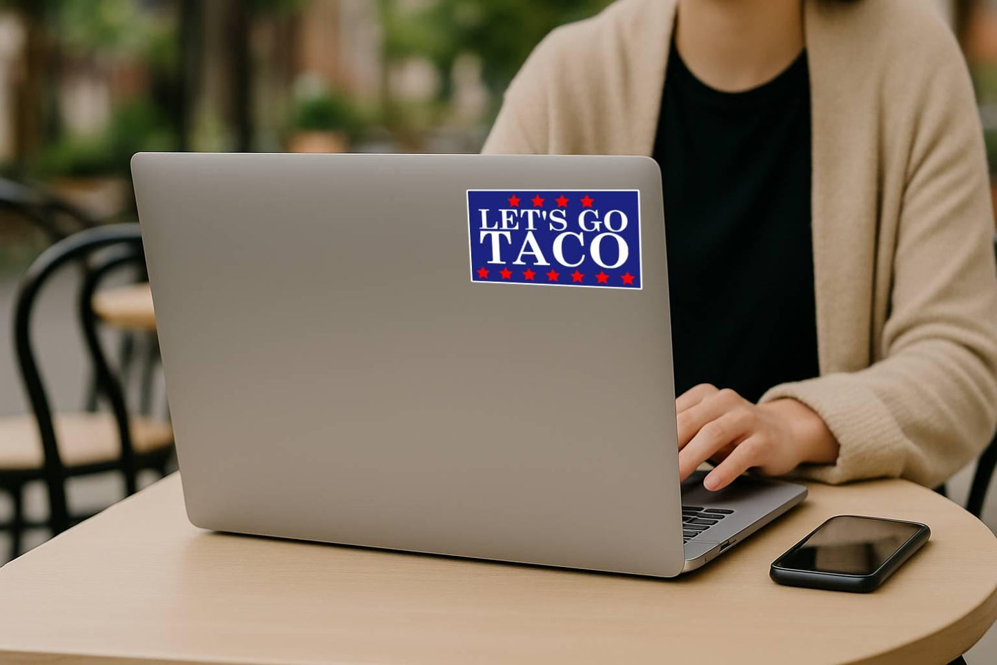 a sticker with the words let's go taco in white with red stars on top and bottom on a blue background on laptop