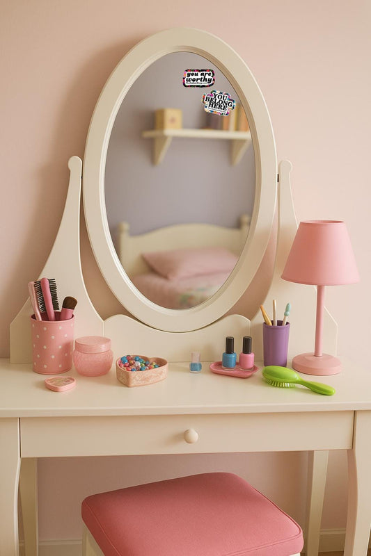 two stickers on the mirror of a little girl's vanity mirror. one says you are worthy and the other says you belong here.