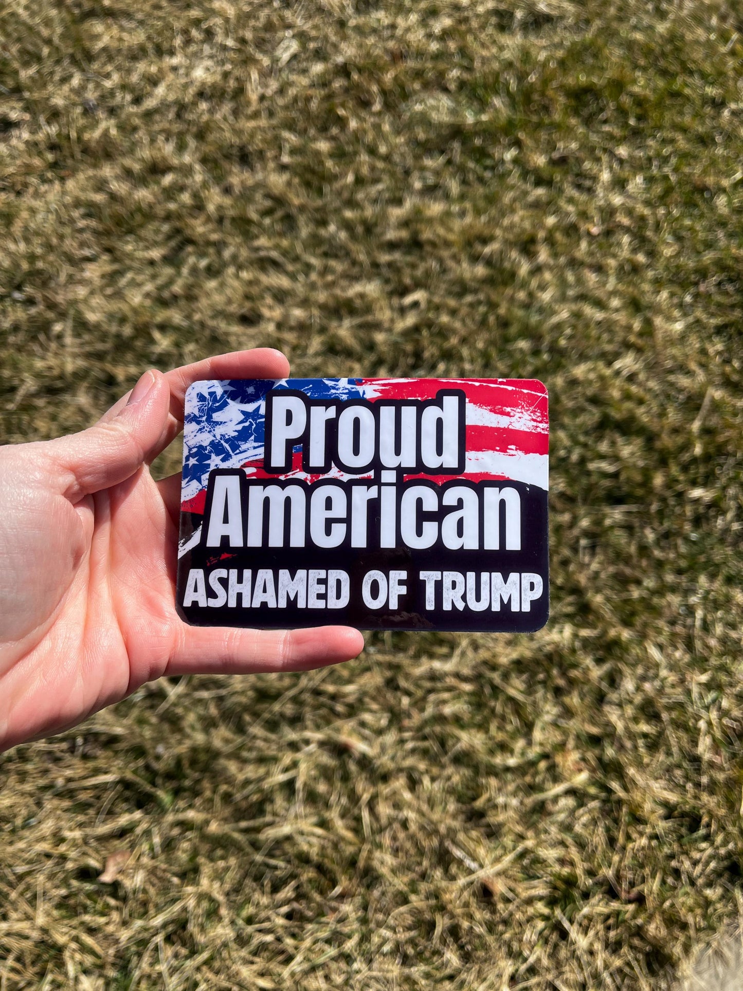Proud American Ashamed of Trump magnet held in hand, standing up for democratic values with unapologetic truth.