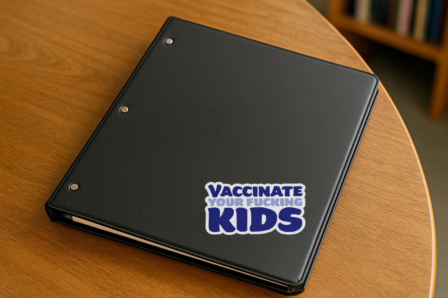 Vaccinate Your Kids' magnet or vinyl decal displayed on a black binder in a library. A bold, high-quality political sticker perfect for cars, laptops, fridges, or toolboxes. Great for activists, protestors, or anyone fed up with fascism.