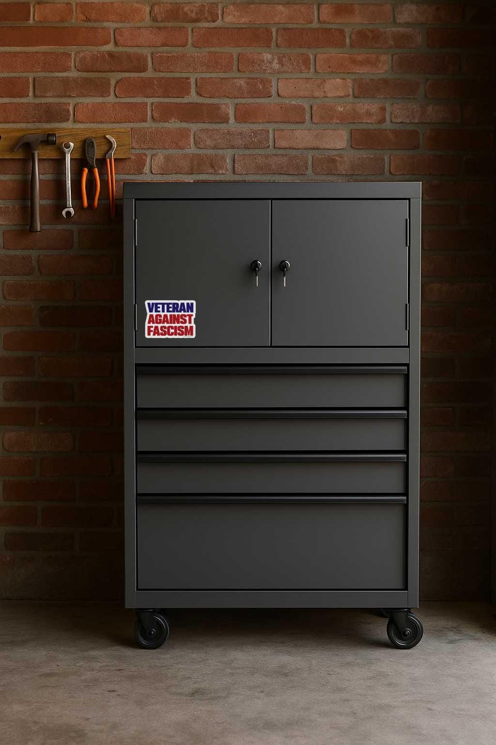 Gray tool cabinet with a 'Veteran Against Fascism' sticker against a brick wall.