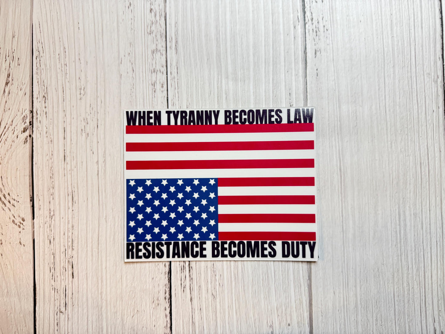 A vinyl decal or magnet displaying the phrase "When tyranny becomes law, resistance becomes duty" in bold lettering, accompanied by an upside-down American flag—a symbol of distress. The design conveys a strong political message about civil resistance.