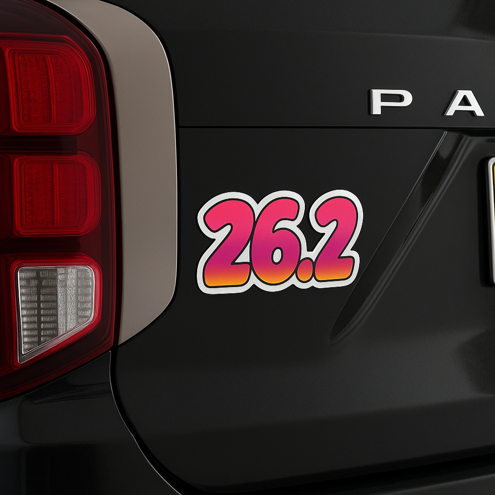 Pink and orange gradient “26.2” marathon magnet placed on the back of a black SUV near the taillight.