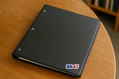 Sticker displaying the numbers “8647” on a black binder resting on a wooden table