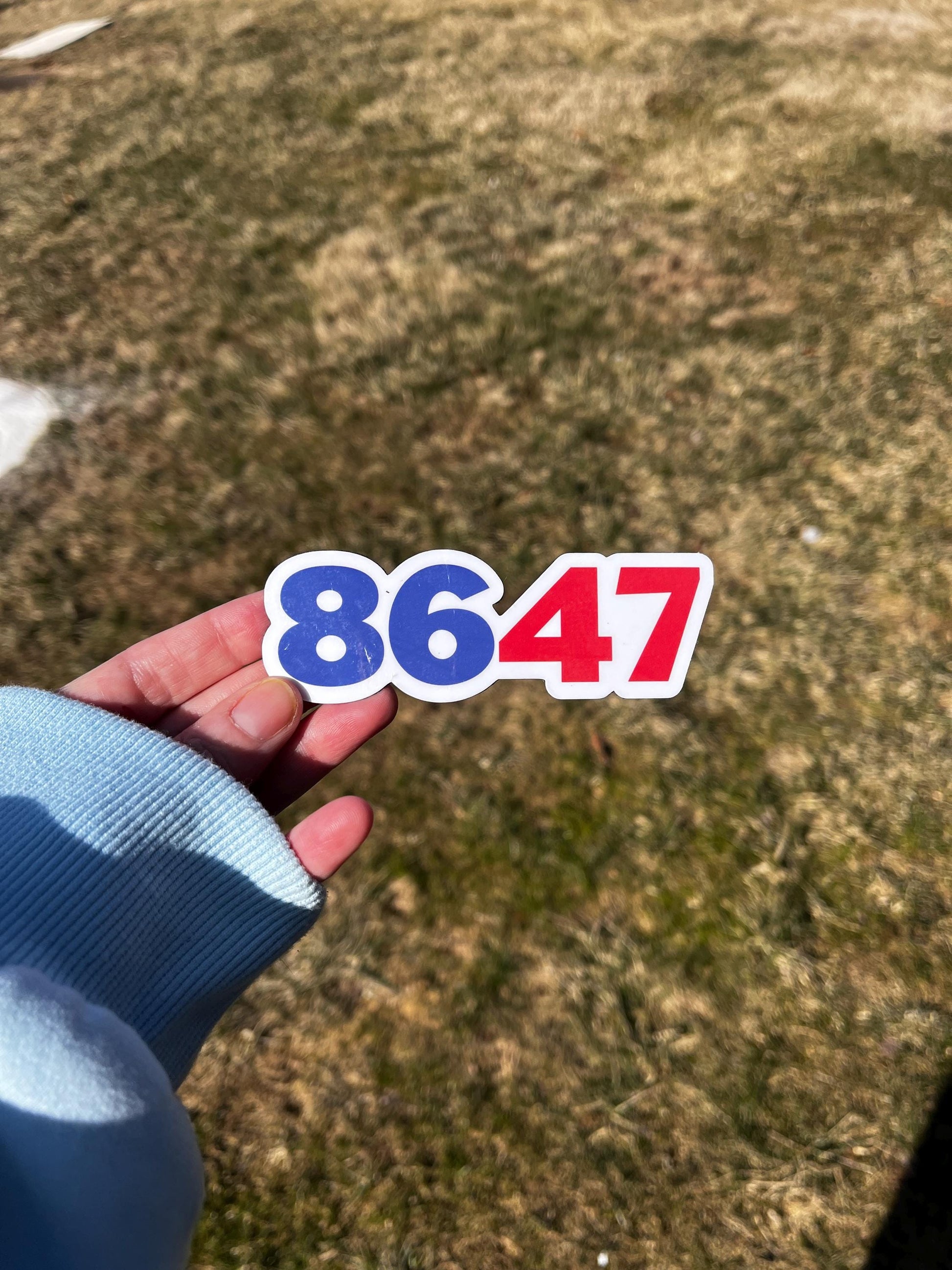 8647 magnet held in hand, representing anti-Trump sentiment and the movement to protect democracy.