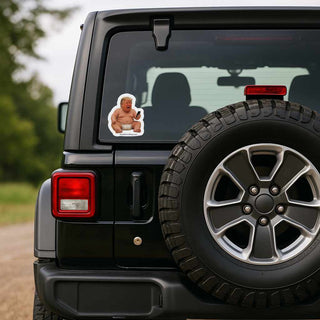 Black SUV with a sticker of a baby Trump on the rear window, outdoors.