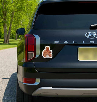 Car with a sticker of a muscular figure on the back, parked outdoors.
