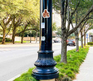 Street lamp post with a sticker on it in an urban setting