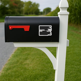 Black mailbox with red flag on a white post in a grassy area