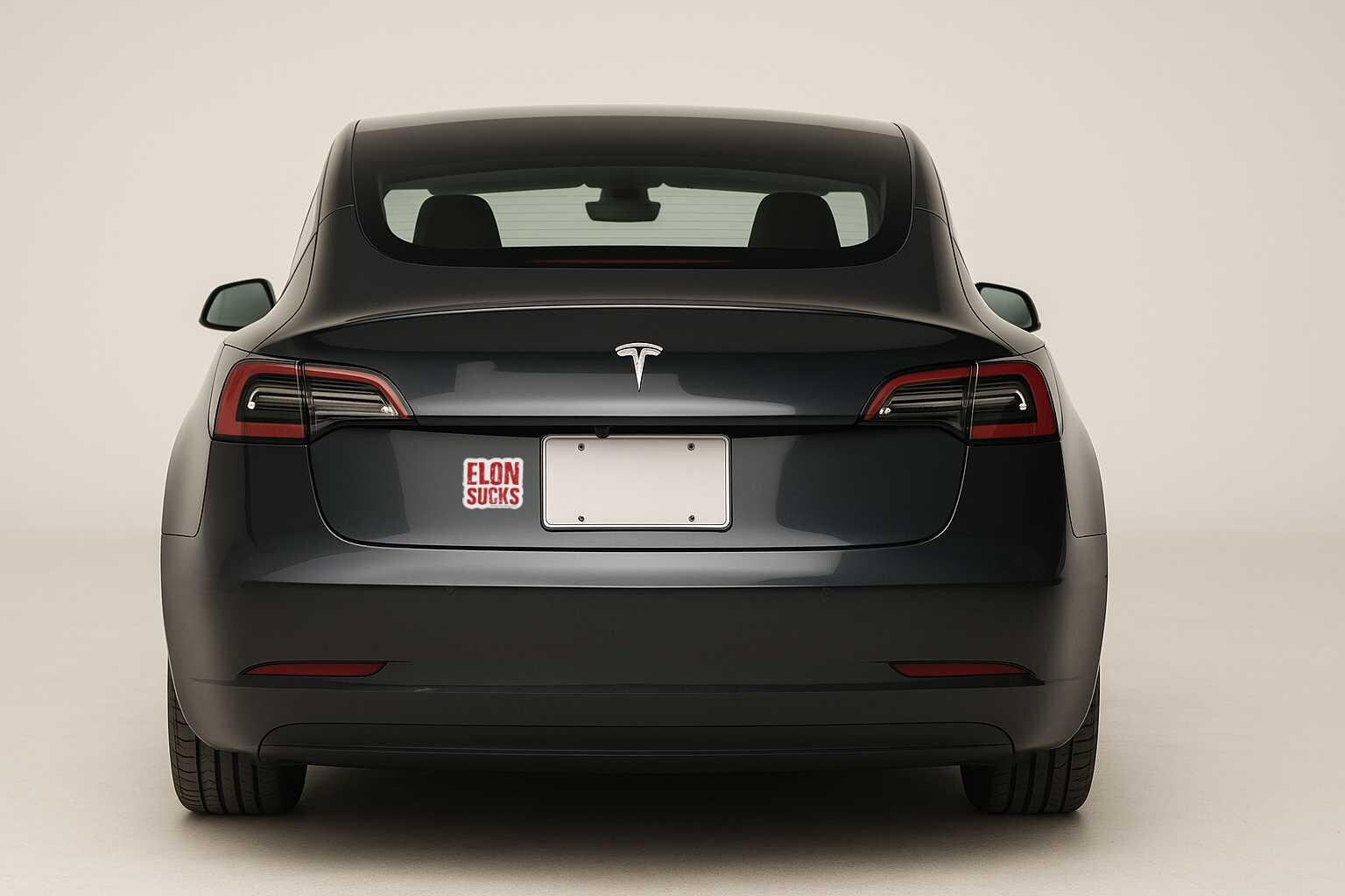 Black Tesla car with a custom license plate on a white background with a sticker that says ELON SUCKS