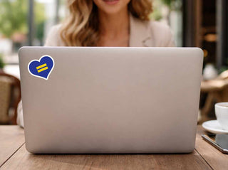 Laptop with a heart-shaped equality sticker on a wooden table, blurred background