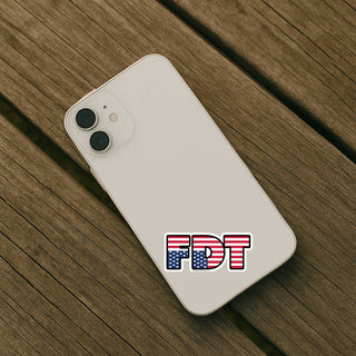 FDT upside down flag sticker applied to the back of a light-colored smartphone resting on a wooden table.