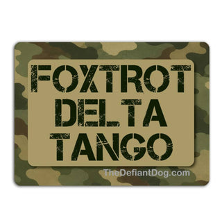 A rectangular camouflage patch or badge with a tan center panel reading 'FOXTROT DELTA TANGO' in distressed black letters, on a plain white background.