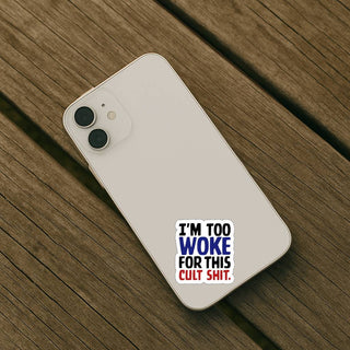 White iPhone on a wooden surface with an ‘I’m too woke for this cult shit’ sticker on the back.