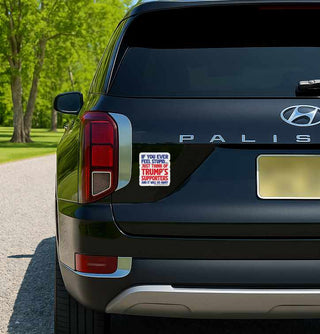 Back of a black Hyundai Palisade with a political bumper sticker on a road.