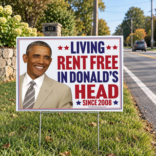 Funny Barack Obama Living Rent Free in Donald's Head Since 2008 political lawn sign installed beside a suburban road, featuring red, white and blue patriotic lettering.