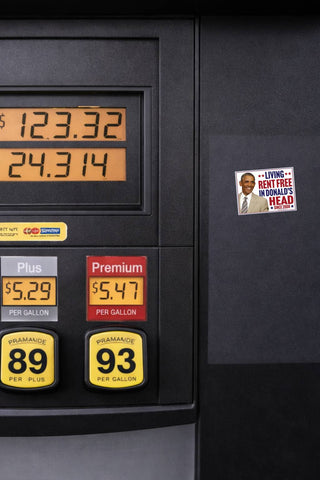 Barack Obama Living Rent Free in Donald's Head political decal displayed on a black gas pump beside fuel price displays.