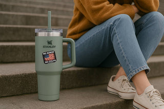 Person sitting on steps with a green Stanley tumbler featuring a patch.