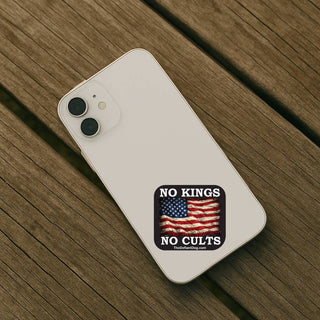 Phone case with 'No Kings No Cults' design on a wooden surface