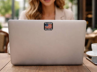 Laptop with a sticker on the back, placed on a wooden table outdoors.