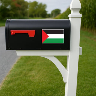 A black mailbox mounted on a white post outdoors, featuring a Palestine flag decal with the text 'FREE PALESTINE' on the front.