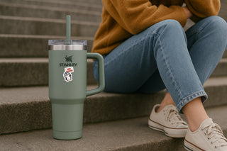 Person sitting on steps with a green Stanley tumbler