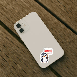 Phone case with a penguin sticker holding a 'Resist' sign on a wooden surface
