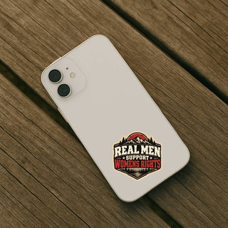 Real Men Support Women’s Rights feminist sticker displayed on white smartphone resting on rustic wooden table.