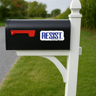 Black mailbox with a 'RESIST' sticker on a white post in a grassy area.