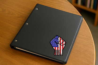 Resist Rebel Revolt Reclaim' magnet or vinyl decal displayed on a black binder in a library. A bold, high-quality political sticker perfect for cars, laptops, fridges, or toolboxes. Great for activists, protestors, or anyone fed up with fascism.