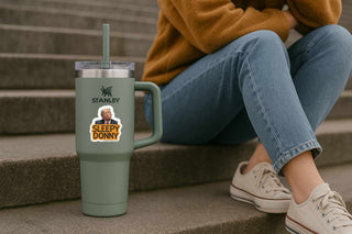 Person sitting on steps with a green Stanley tumbler featuring a 'Sleepy Donny' sticker.
