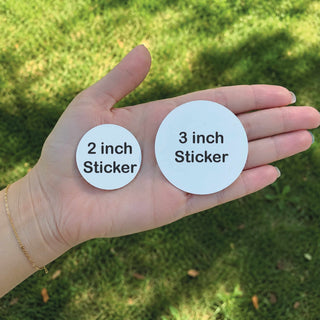 woman hand holding 2 inch and 3 inch circle sticker size comparison blank white vinyl decal outdoor background