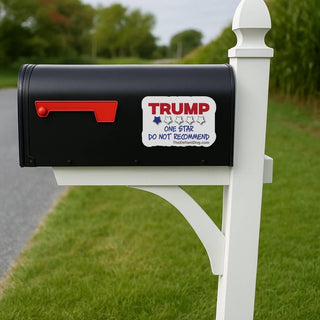 Black mailbox with a 'TRUMP One Star Do Not Recommend' sticker on a white post outdoors.