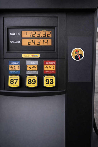 Round political satire sticker featuring a clown-style Trump portrait with rainbow hair and halo applied to a gas station pump, showcasing outdoor durability and visibility on public surfaces.