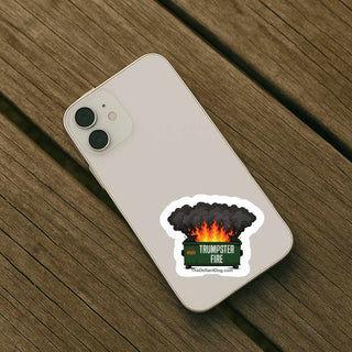 Trumpster Fire anti Trump political sticker displayed on a smartphone featuring a colorful dumpster fire cartoon with flames and smoke