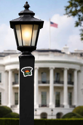 Trumpster Fire anti Trump sticker displayed on a lamp post near the White House featuring a cartoon dumpster fire political satire design