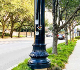 Trumpster Fire anti Trump sticker attached to a city light pole featuring a burning dumpster cartoon and political satire artwork for democracy supporters