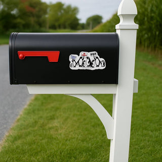 A mockup of the sticker applied to the side of a classic black mailbox with a red flag. The mailbox is mounted on a white post along a rural road with green fields in the background.