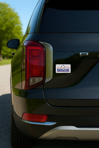 A tight close-up of the rear corner of a dark-colored modern SUV. The "Are We Great Yet?" vinyl decal is applied to the body of the car, situated between the red taillight and the rear hatch.