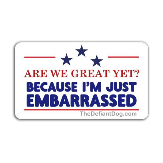 A high-resolution digital mockup of a rectangular vinyl decal with a slight drop shadow against a plain white background. The decal features the text "ARE WE GREAT YET? BECAUSE I'M JUST EMBARRASSED" in red and blue, topped with three blue stars and the website TheDefiantDog.com at the bottom.