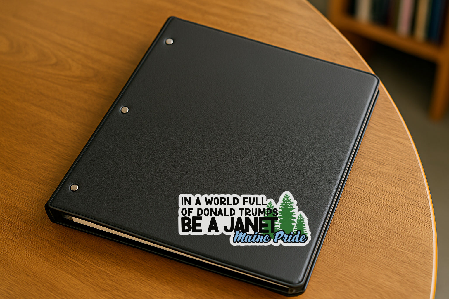 'In a World of Donald Trumps Be a Janet' magnet or vinyl decal displayed with a slight shadow on a white background. A bold, high-quality political sticker perfect for cars, laptops, fridges, or toolboxes. Great for activists, protestors, or anyone fed up with fascism.