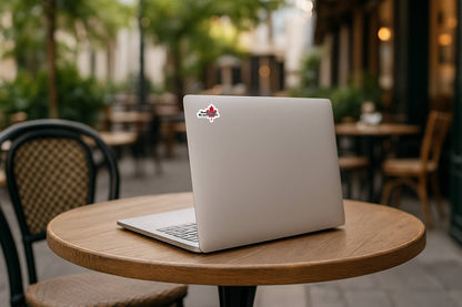 Laptop with a maple leaf sticker on a wooden table outdoors