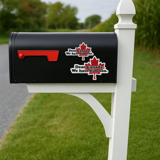 Black mailbox with red and white stickers on a white post in a grassy area.