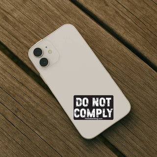 Phone case with 'Do Not Comply' text on a wooden surface