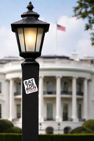 Lamp post with 'Eat the Rich' sticker in front of the White House