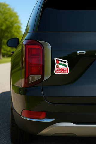 A close-up rear view of a black SUV parked outdoors, showing a small rectangular sticker on the quarter panel. The sticker features a stylized Palestinian flag with the text 'END THE GENOCIDE' in red on a white background.