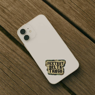 White phone with a 'Foxtrot Delta Tango' sticker on a wooden surface